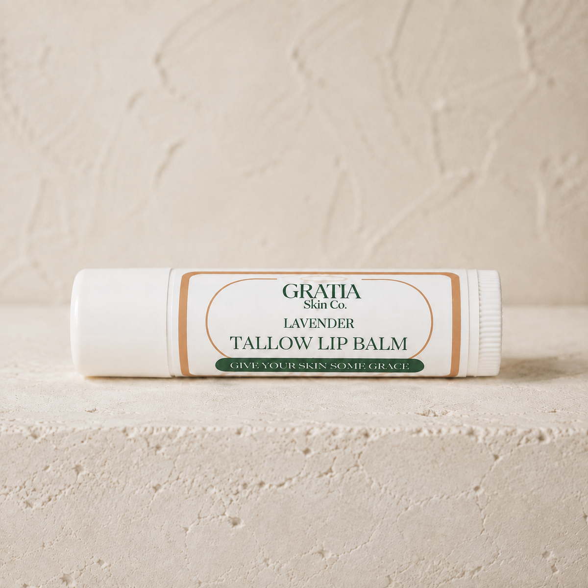 Gratia Skin Co. Lavender grass-fed tallow lip balm tube shown sideways with a neutral white horizontal label